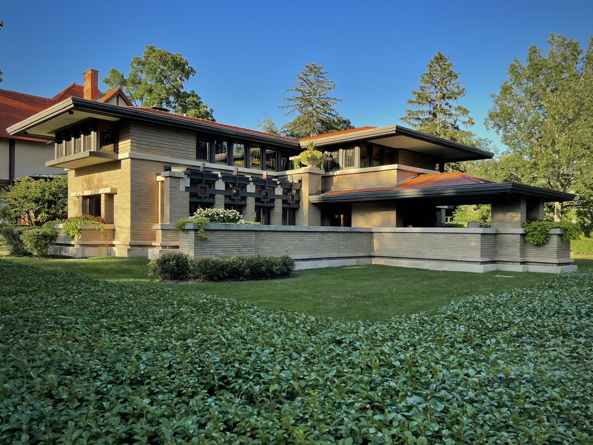 The Meyer May House in Heritage Hill, a low Frank Lloyd Wright Prairie house of tan brick with deep overhanging eaves, photographed on a sunny day